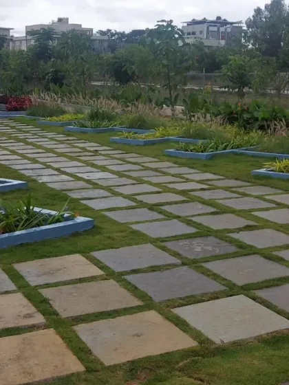A large paved area using square flagstones with grass growing in the joints. This 'checkerboard' style is a modern and permeable solution for large patios or public plazas.
