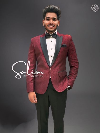 A client smiling in a maroon patterned tuxedo jacket. The subtle pattern adds depth and interest to the classic silhouette.