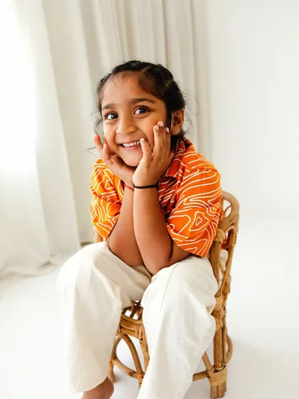 A charming portrait of a toddler in a bright, traditional shirt. His expressive smile shows that themed and styled sessions are fun for older kids too.