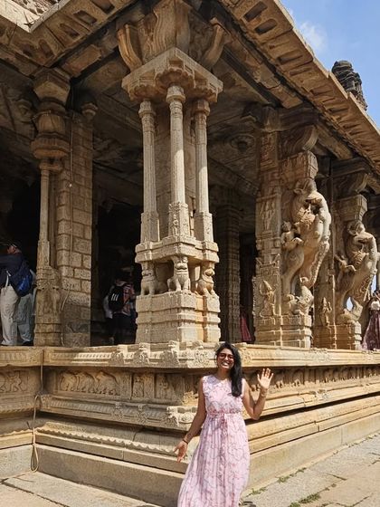 A candid shot of a traveler waving from inside a Hampi temple.