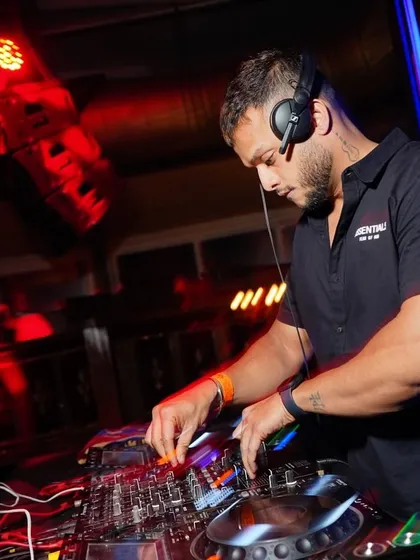 Focused and in the zone at OPA Bar & Cafe. This close-up shot captures the concentration it takes to mix a seamless set under the intense red glow of club lights.