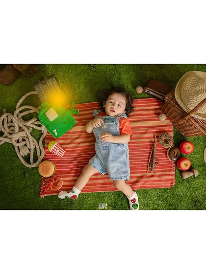 A baby enjoying a picnic in a fantasy setting, complete with a hobbit hole backdrop.