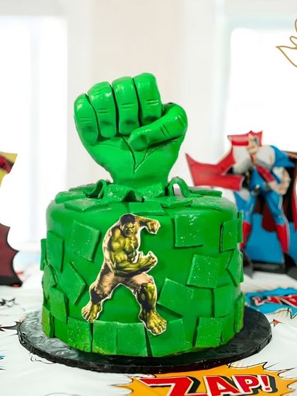 Hulk smash! This powerful cake features the Hulk's mighty green fist bursting through, creating a dynamic and exciting centerpiece for a fan of the strongest Avenger.