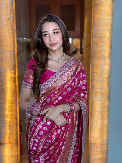 The warm lighting in this shot enhances the richness of the pink saree and the glow of her makeup.
