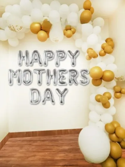 An elegant 'Happy Mother's Day' setup with a white and gold balloon garland.