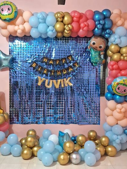 A Cocomelon theme for Yuvik's first birthday. I used a blue sequin backdrop framed by a balloon garland in the theme's colors, complete with Cocomelon character balloons and a large gold number '1' to celebrate the big milestone.