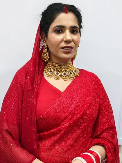 A basic but beautiful makeup and hair look for a festive occasion. The hair is neatly pulled back to highlight her traditional red saree and gold jewelry.