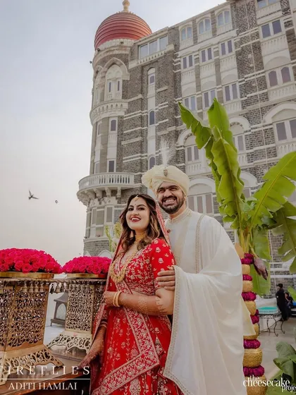 A beautiful portrait of Vijayshree and Omkar at their wedding, with the iconic Taj Mahal Palace hotel as the backdrop. The traditional decor elements like the banana tree perfectly frame this timeless shot.