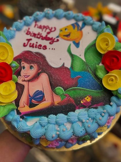An underwater fantasy with this Little Mermaid photo cake. The edible image of Ariel is surrounded by colorful frosting roses and under-the-sea details.
