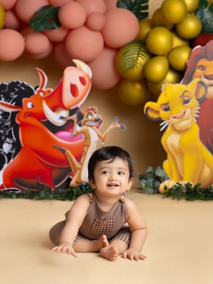 A happy moment from our Lion King themed first birthday shoot. The colorful character cutouts and balloon garland make the perfect backdrop for this little cub.