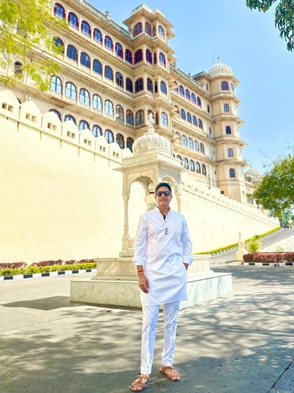 Standing in front of a beautiful white palace in Udaipur. The crisp white kurta complements the sun-bleached architecture perfectly.