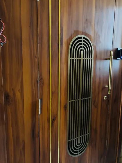A close-up of the wooden safety door's brass grill and handle, highlighting the quality of the materials used.