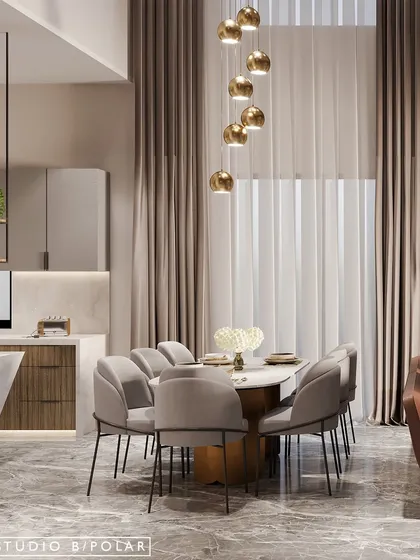 The dining area is defined by a cascade of golden pendant lights that hang from the double-height ceiling, creating a dramatic and elegant focal point over the marble-topped table.
