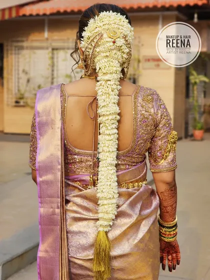 The back view of Nidhi's hairstyle, showcasing a traditional South Indian braid adorned with a full length of fresh jasmine flowers (mallige) and a beautiful hair accessory.