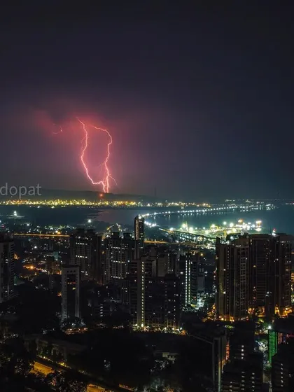 A dramatic drone photograph capturing a powerful red lightning strike over the Mumbai coastline and the Trans Harbour Link at night.