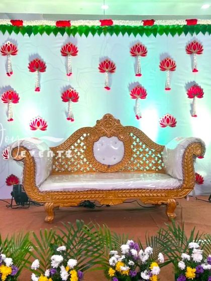 For this puberty function, we created a backdrop with hanging lotus flower motifs made from red and white petals. The stage is set with an ornate white and gold divan for the main seating.