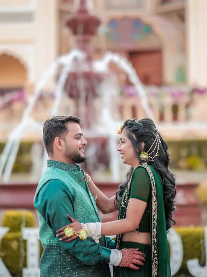 A romantic portrait of a couple during their Mehendi ceremony, with a fountain in the background.