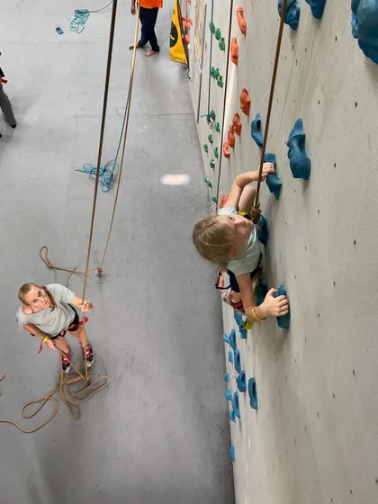 A unique perspective showing a young climber being belayed by her friend. It's a great way to teach responsibility and trust.