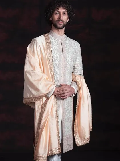 This is my vision of a modern groom's sherwani. It blends classic charm with a clean, minimalist grace, featuring fine, all-over embroidery on a structured silhouette. The ensemble is completed with a pure silk stole, creating a look of refinement without being loud.