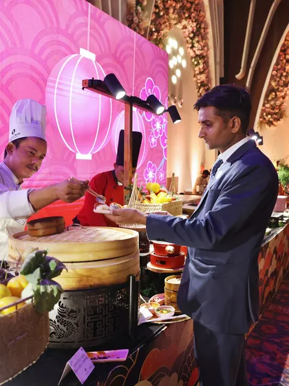 A guest receives a freshly made dumpling from our chef at the "Naoki" Pan-Asian station. We love creating these moments of direct interaction.