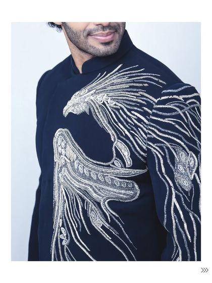 A close-up of the powerful phoenix embroidery on this navy bandhgala jacket. The silver and white threadwork creates a dynamic, eye-catching design that’s both artistic and masculine.