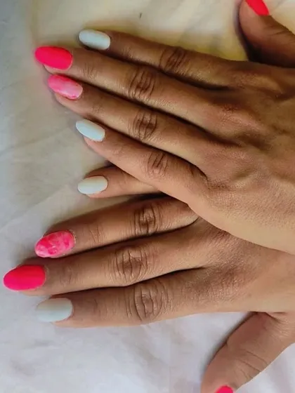 A full view of the hands showing the alternating pink and white nail art, a great style for a birthday or summer party.