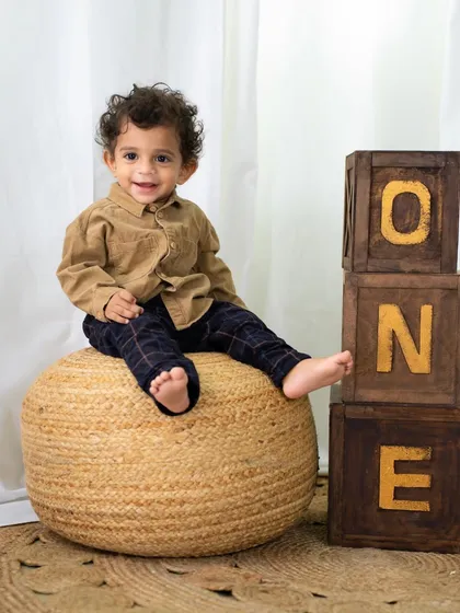 A proud smile as he sits on the pouf next to his "ONE" blocks. A perfect way to celebrate his first birthday.