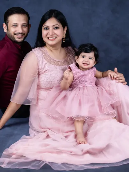 An elegant family portrait with everyone dressed in shades of pink. The mother's flowing dress adds a touch of grace to this beautiful seated photo.