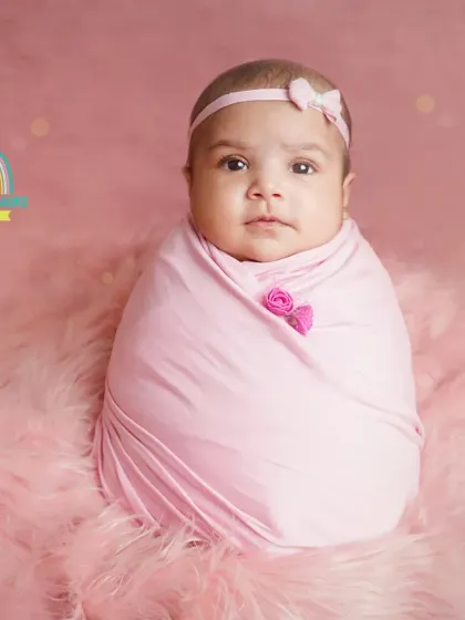 A simple and sweet portrait of a 2-month-old wrapped in pink, looking right at the camera.