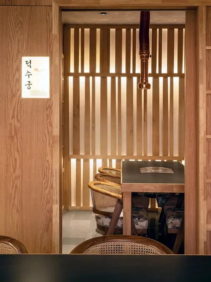 This view into a private dining area showcases the clean lines and warm minimalism that define the Japandi influence. The simple wooden furniture and subtle lighting create a serene atmosphere for a more personal dining ritual.