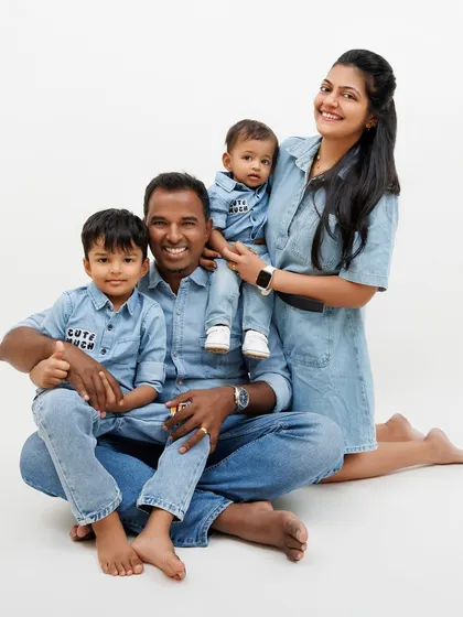 A happy family of four, all dressed in denim, posing together for a classic and joyful studio portrait.