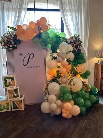 The main backdrop for the tropical baby shower, with 'Little P coming soon' signage, wooden baby blocks, and a lush arrangement of balloons and florals.
