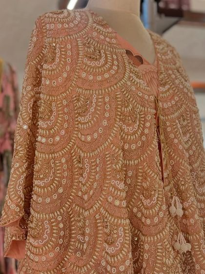 A detailed shot of a heavily beaded and sequined capelet in a beautiful scalloped pattern, a true work of art.