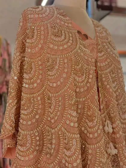A detailed shot of a heavily beaded and sequined capelet in a beautiful scalloped pattern, a true work of art.