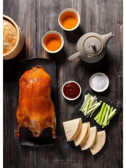 A whole Peking Duck, expertly roasted and presented for the new menu at Shang Palace. This overhead shot captures the full presentation with pancakes, sauces, and garnishes.