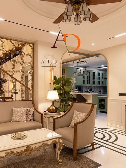 A neo-classical living room with elegant furniture, a decorative metal screen for the staircase, and striking black and white marble inlay flooring.