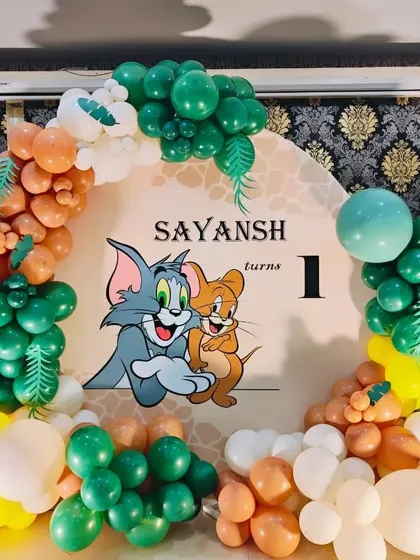 A close-up of the Tom and Jerry backdrop and balloon arch, featuring jungle-inspired colors.