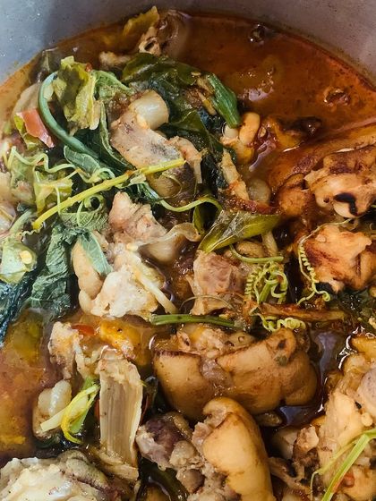 A pot of pig trotters cooked with tender pumpkin shoots.