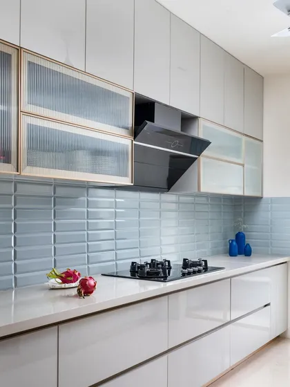 Our kitchens are designed to be the heart of the home, both beautiful and highly functional. Here, we paired sleek, handleless cabinetry with a pop of pastel blue subway tiles and fluted glass shutters, proving that practical spaces can also be full of personality.
