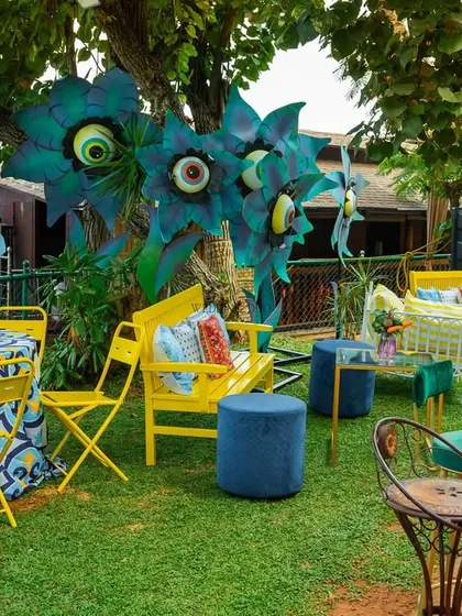 A vibrant lounge area for a lakeside Mehendi. Bright yellow and blue furniture, printed tablecloths, and our signature quirky flower installations create a fun and relaxed atmosphere.