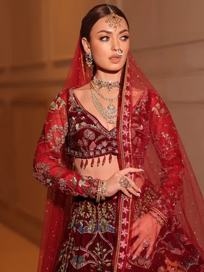 A full view of the bride in her red velvet lehenga. The styling is designed to be both grand and elegant, perfect for a winter wedding.