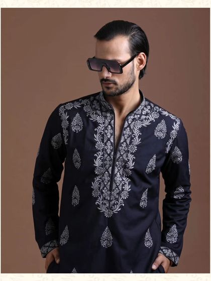 A detailed shot of a navy kurta with heavy, traditional paisley embroidery. This showcases the artistry and skill involved in creating a truly standout ceremonial piece.