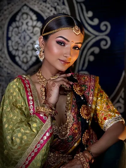 I love the elegance of South Indian bridal makeup. This look features a warm, golden complexion, eyes accentuated with a pop of pink shadow, and traditional temple jewelry. The braided hairstyle adorned with fresh flowers is a key element that I meticulously craft to complete the authentic look.
