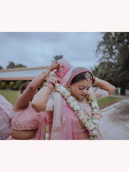 A bridesmaid helping the bride with her veil, a beautiful candid moment of support.
