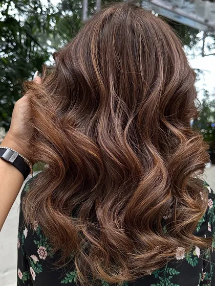 This client flew in from Dubai for my signature 'Caramello' color. I blended caramel highlights into her hair and covered her greys for a fresh, youthful look. The final style with soft waves really shows off the dimension.