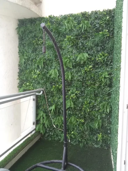 A balcony corner transformed with a vertical garden, creating a cozy nook for a swing chair.