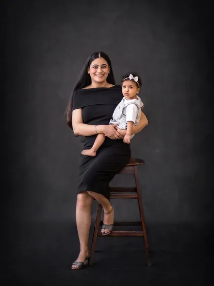An elegant portrait of a mother and her baby girl. The simple black dress and dark background create a timeless and sophisticated look.