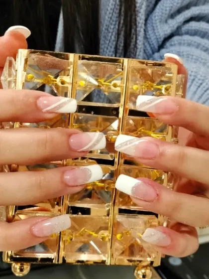 I love creating modern twists on classic styles. This look features a soft, natural base with a clean white tip and a delicate silver glitter swirl for an elegant finish. It is a beautiful example of a custom French manicure on nail extensions.