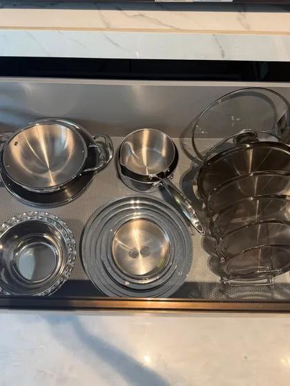 A drawer containing steel serving dishes and pots. By grouping similar items together, we create a clean, organized look that is easy to maintain.