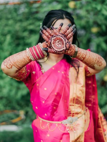 A playful pose from the bride, highlighting her beautiful engagement mehendi. The circular patterns on her palms are the centerpiece of the design.